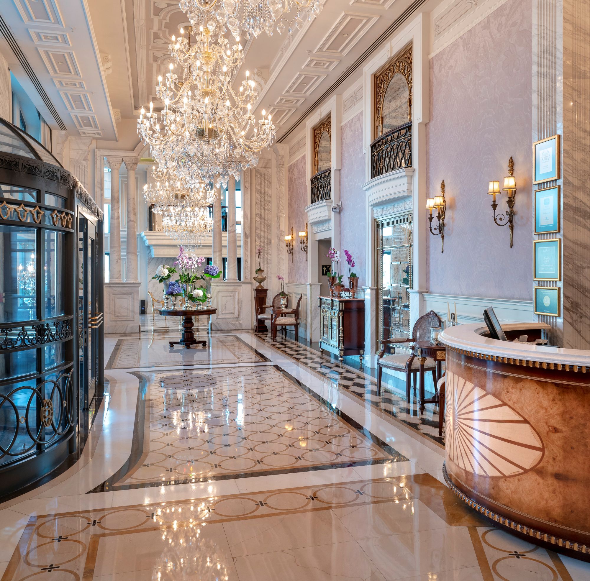 Luksusowe lobby hotelu Rixos Pera Istanbul charakteryzuje się wysokimi sufitami, eleganckimi żyrandolami, marmurowymi podłogami, okrągłą recepcją i dużymi oknami wpuszczającymi naturalne światło.